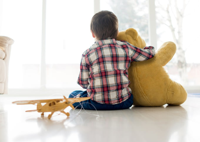 Portrait of child sitting in living room with Teddy bear