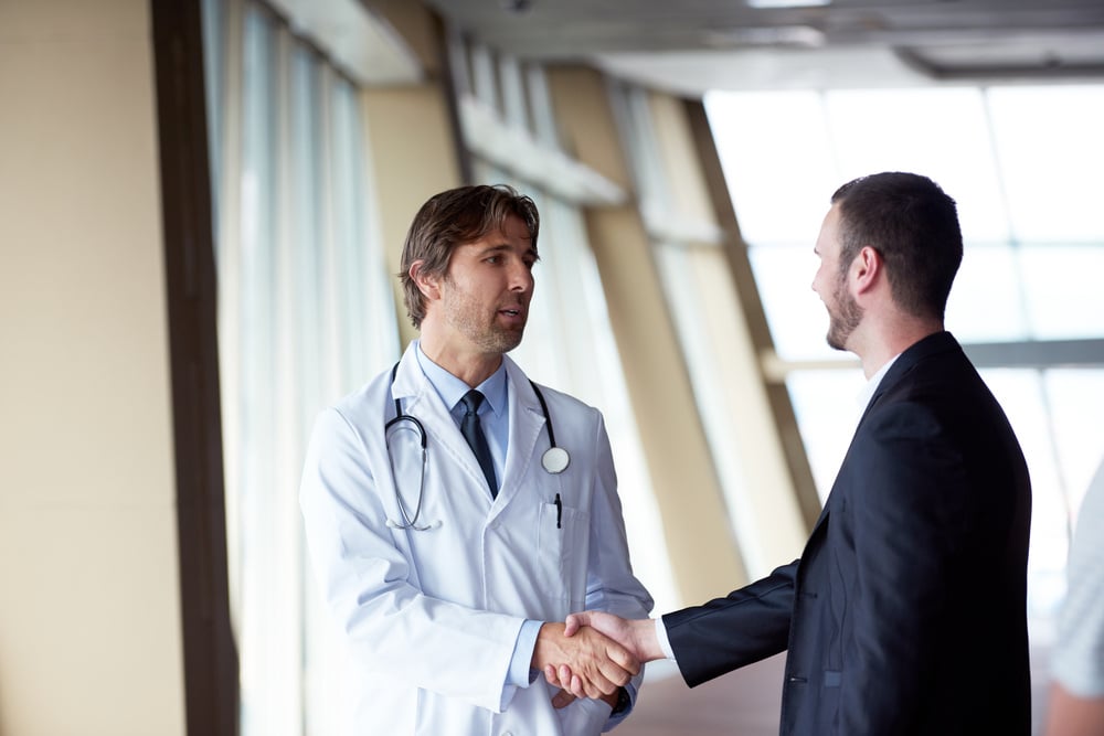 doctor handshake with a patient at doctors bright modern office in hospital